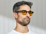 Modellen bär LEMTOSH i Grey-Brown Fade i storlek 46 med Mellow Yellow tonade linser.