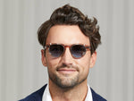 Model is wearing The MAYDELA CLIP in Gold in size 49 with Denim Blue Tinted Lenses