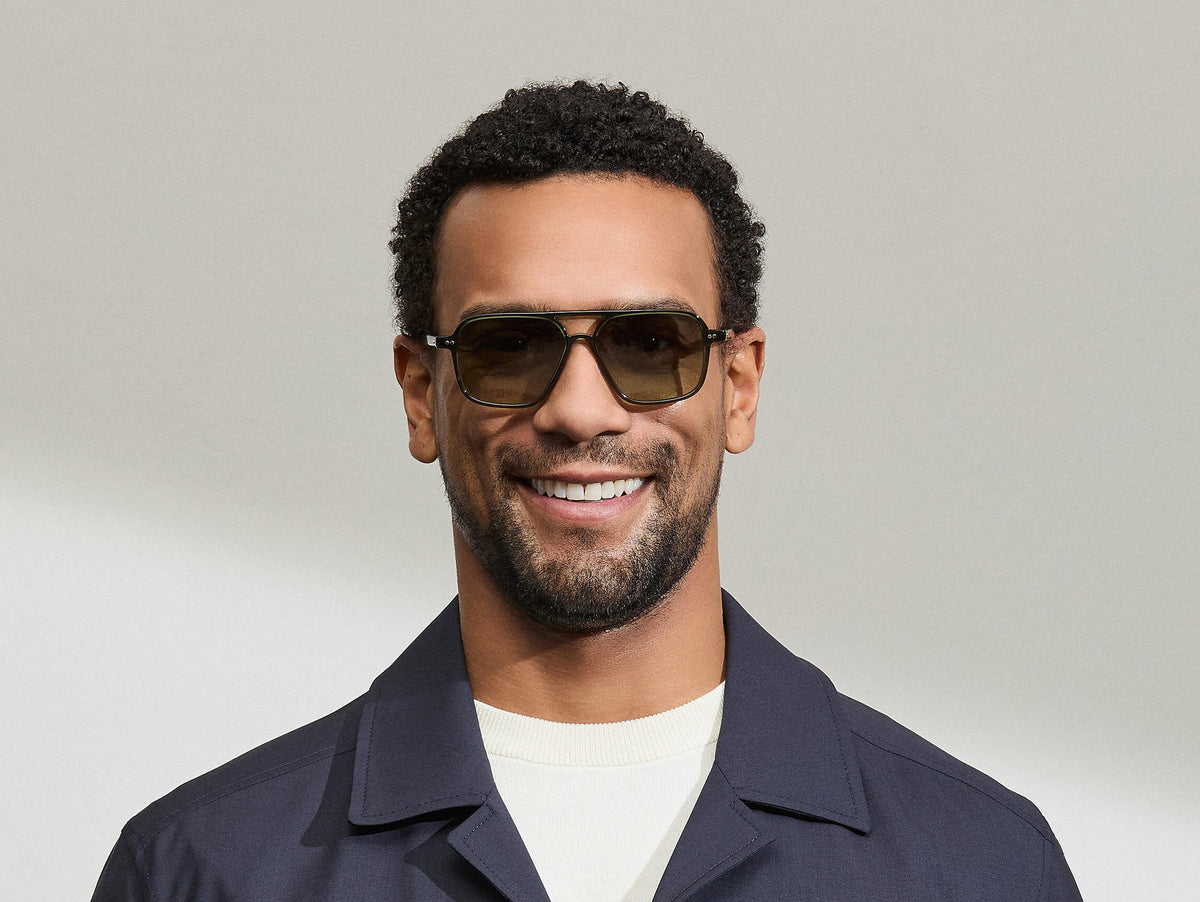 Model is wearing The MINYAN SUN in size 54 in Dark Green with Forest Wood Tinted Lenses