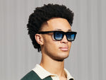 El modelo lleva el RIZIK en Black en talla 49 con lentes tintadas Broadway Blue Fade.